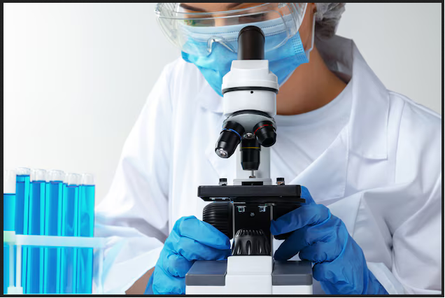 Woman looking through microscope lenses, with professional laboratory protection